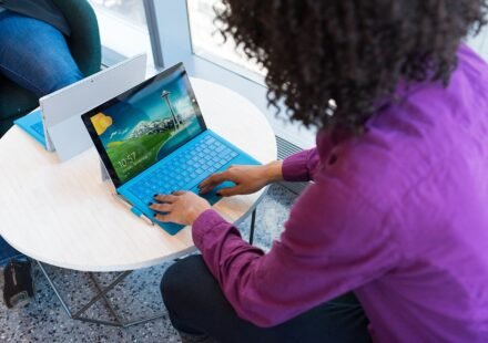Person typing on a laptop at a small round table in an office lounge