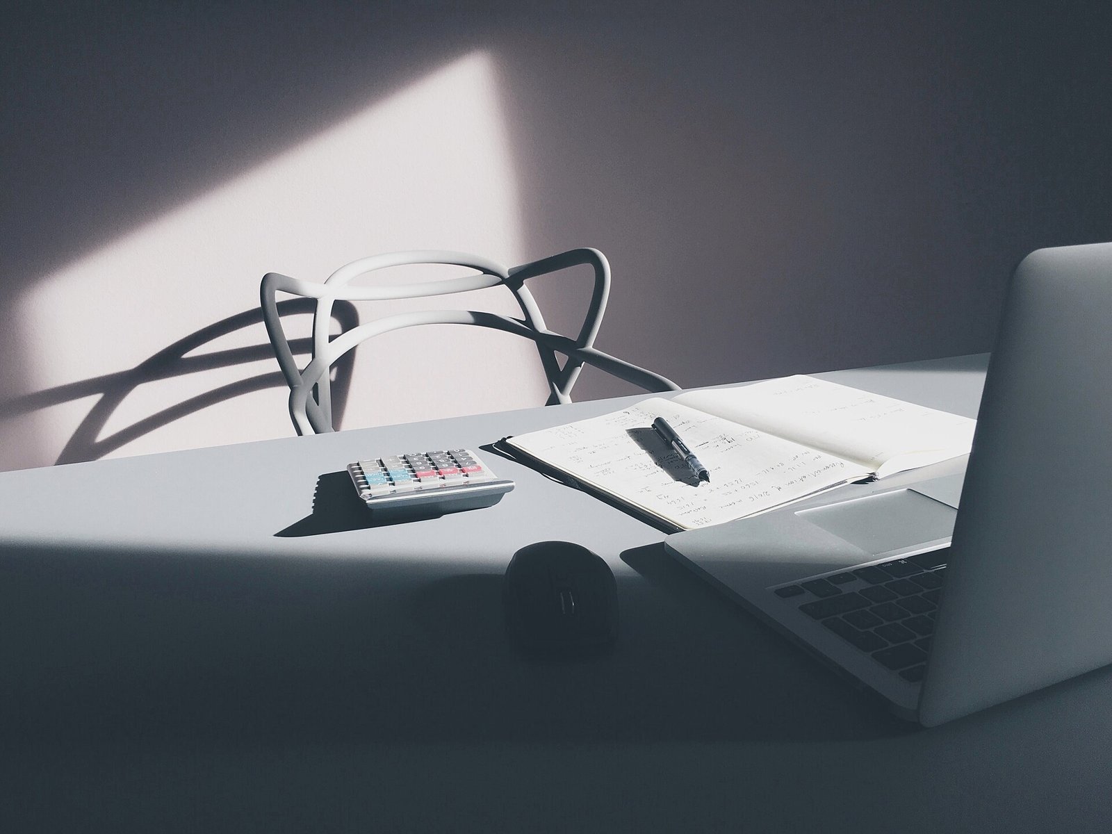 Desk with a laptop, a calculator and an open notebook