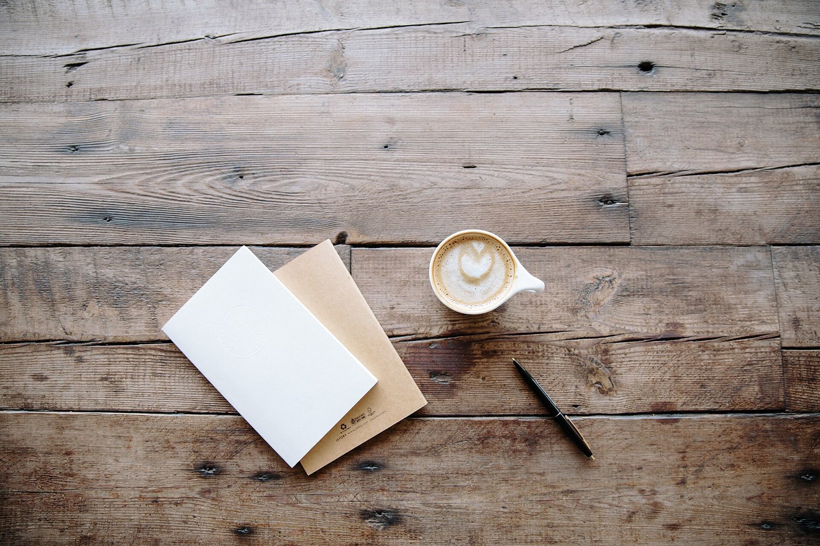 Notebook, pen and coffee on a wooden table