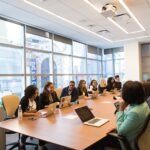 Team meeting around a long conference table with laptops open