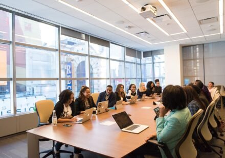 Team meeting around a long conference table with laptops open