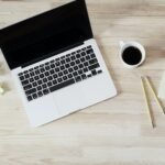 Open laptop next to a cup of coffee on a wooden desk