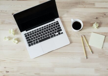 Open laptop next to a cup of coffee on a wooden desk