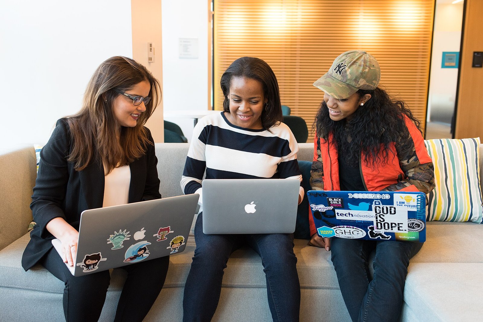 Team of colleagues working together on laptops on a couch