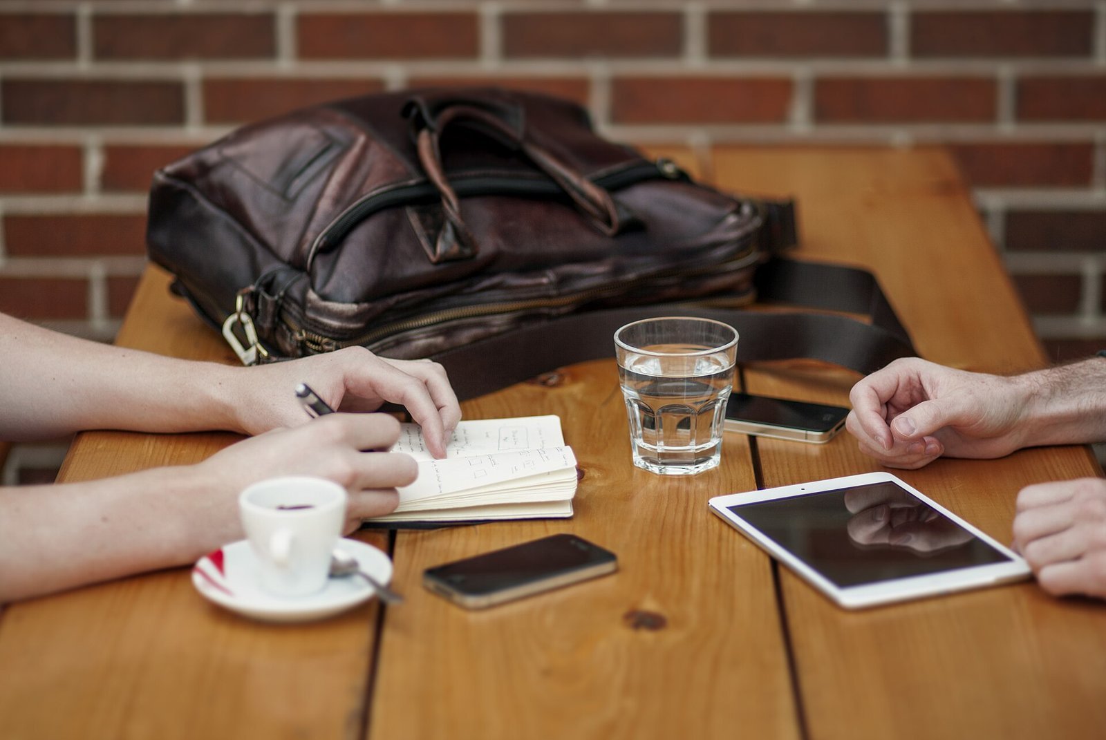 Two people meeting at a table with a phone, tablet and coffee