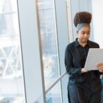 Woman reading information on a tablet while standing in a bright office