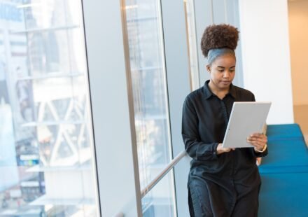 Woman reading information on a tablet while standing in a bright office