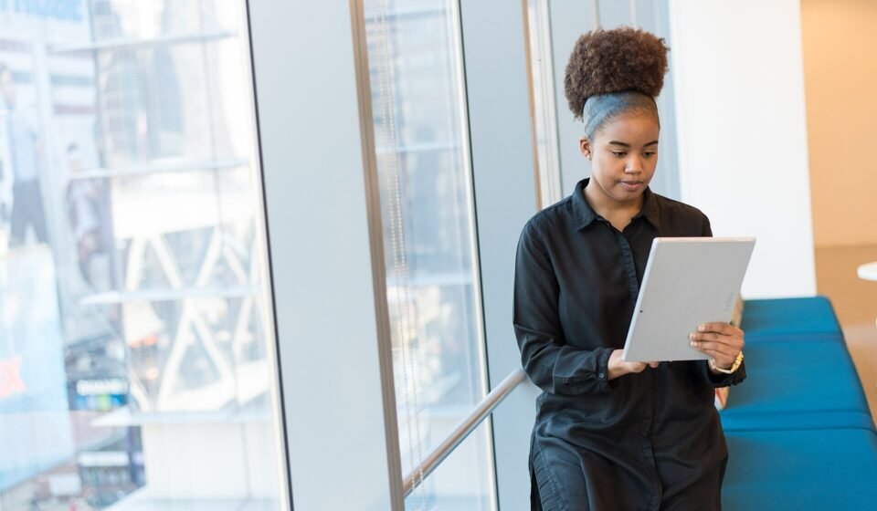 monday.com CRM Review 2026: Can It Replace Salesforce or HubSpot? Woman reading information on a tablet while standing in a bright office