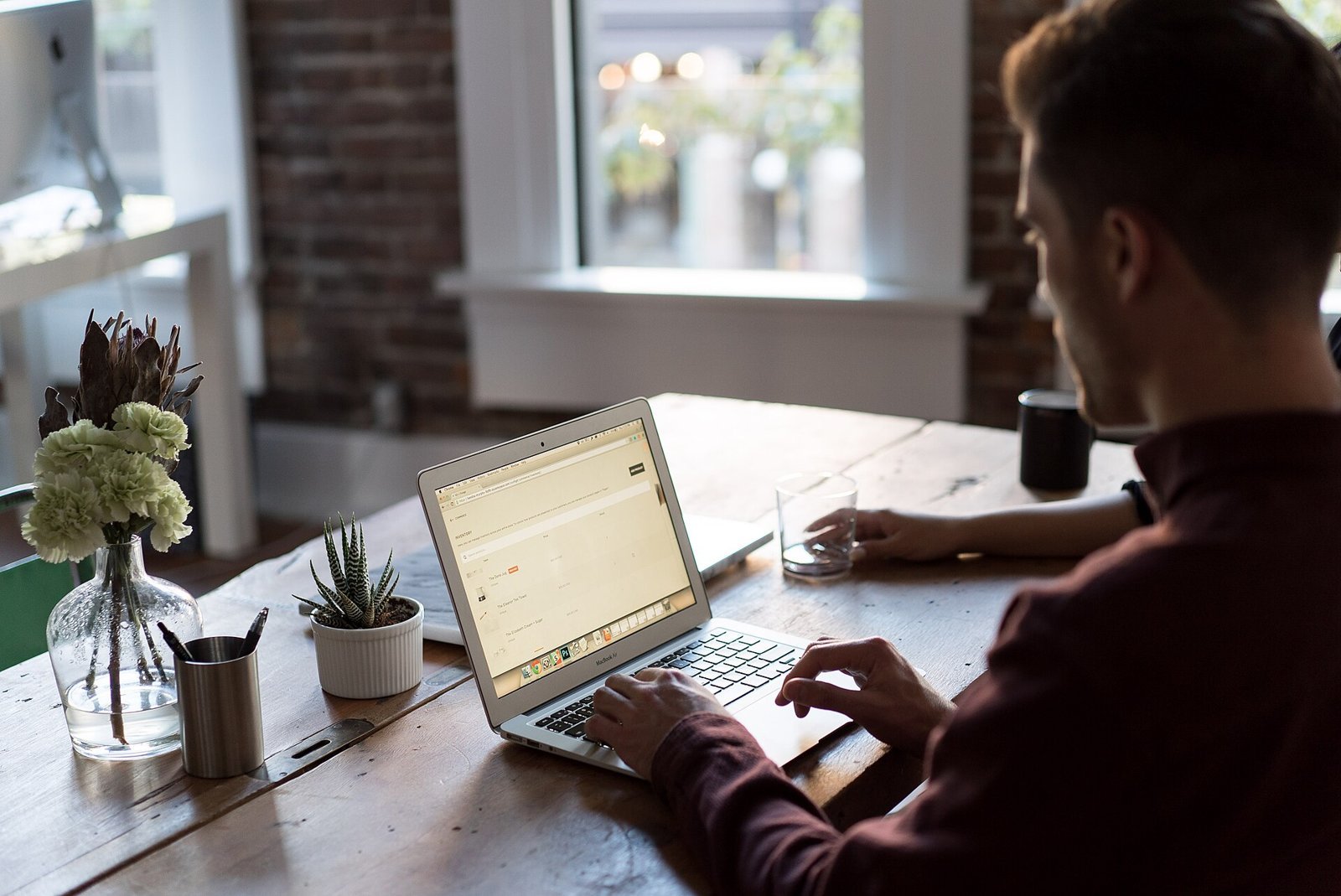 Person working on a laptop at a desk by a window