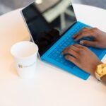 Person typing on a laptop at a small round table