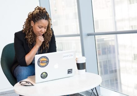 Woman sitting at a laptop with her hand on her chin, thinking through a problem