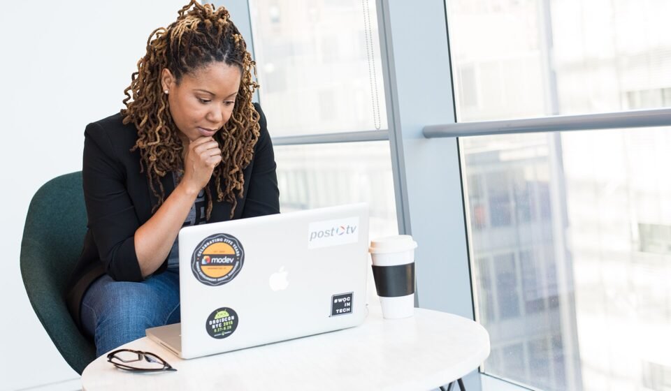 Smartsheet Automation Not Triggering? 9 Causes and the Fix for Each Woman sitting at a laptop with her hand on her chin, thinking through a problem