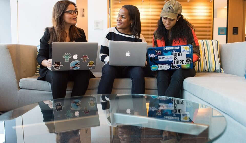 Wrike vs Teamwork.com 2026: Which Is Better for Agencies and Client Work? Small team working together on laptops on a couch