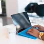 Laptop open on a desk next to a Microsoft coffee cup