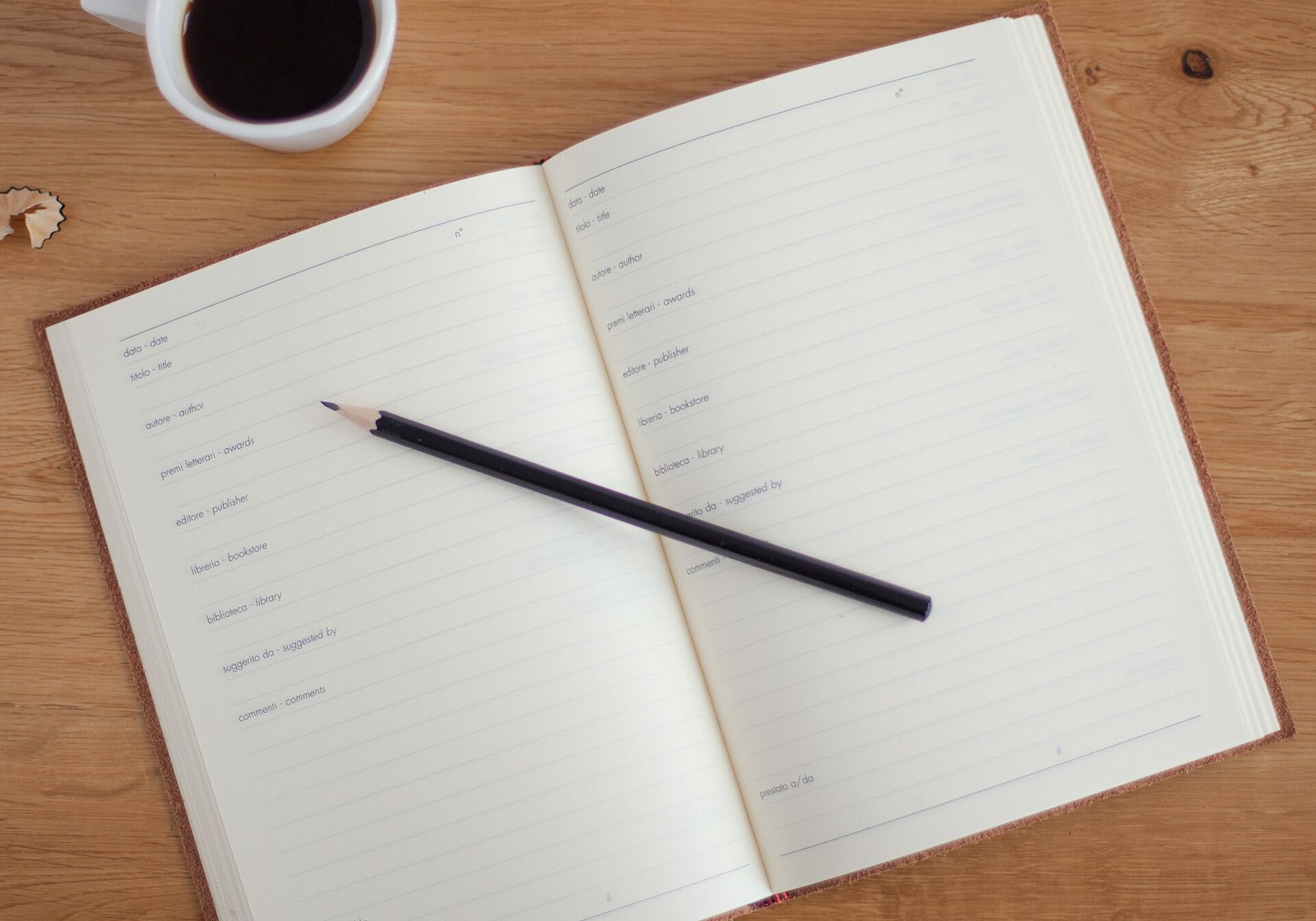 Open notebook with a pencil next to a cup of coffee