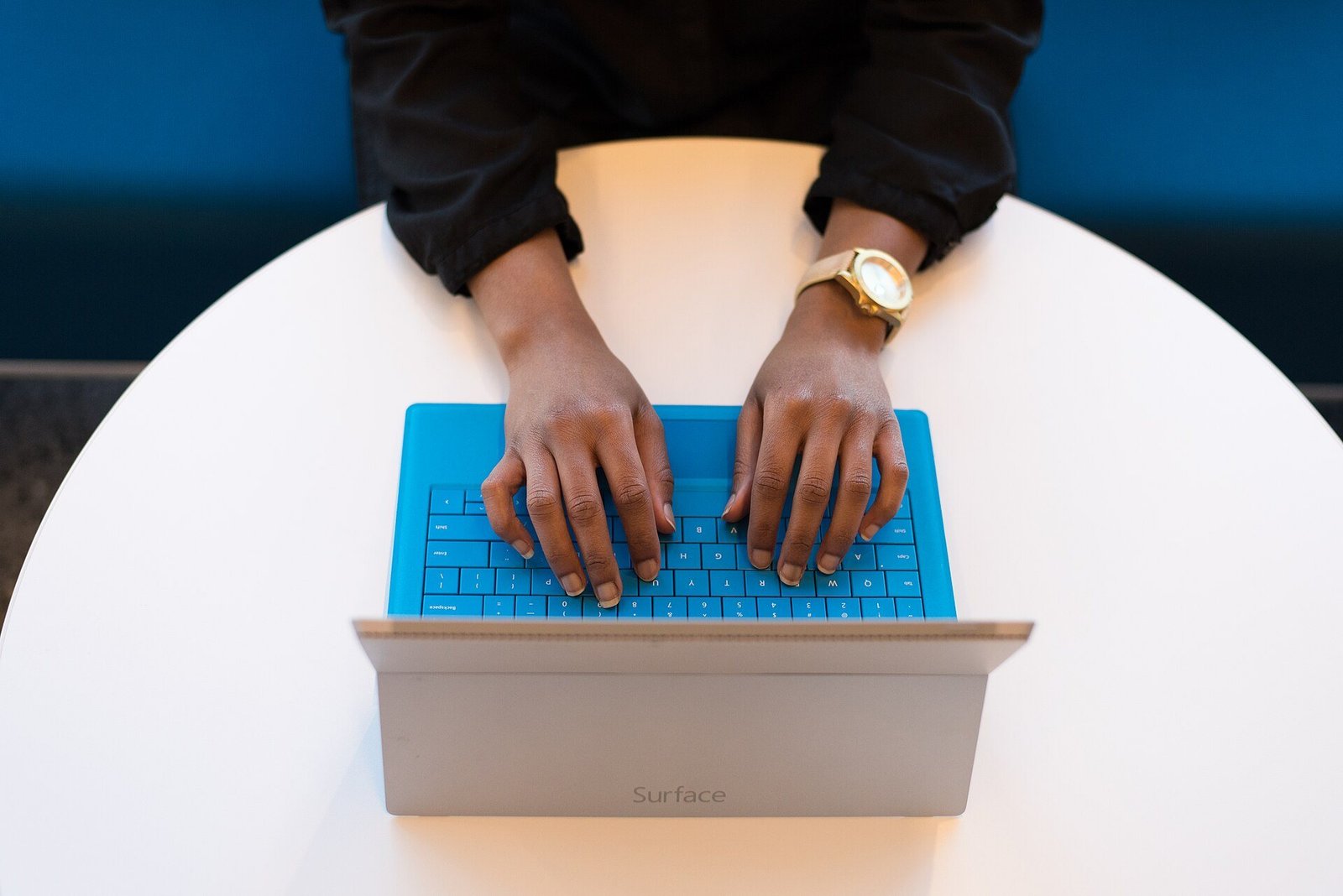Hands typing on a laptop keyboard on a round white desk