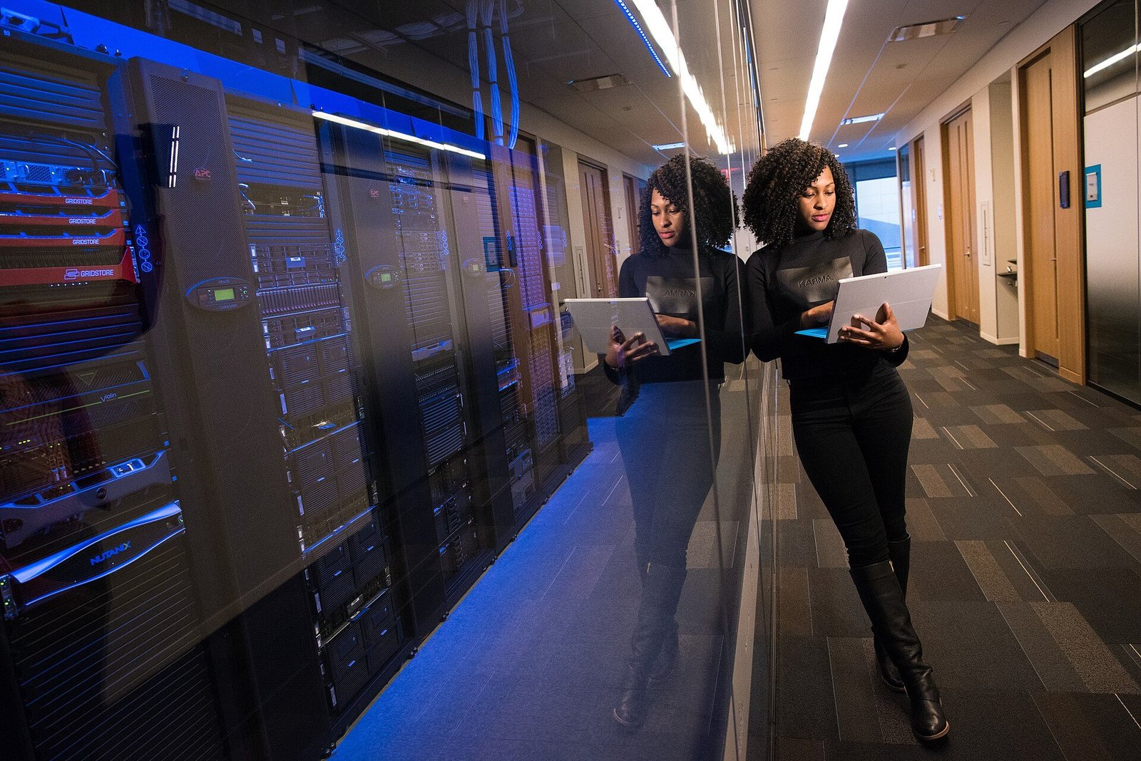 Analyst holding a tablet in a corridor lined with server racks