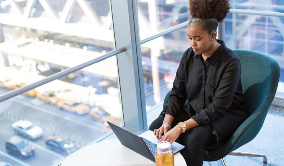 ClickUp AI for Remote Teams (2026): What Actually Helps Engagement and What It Costs Remote worker using a laptop by a large window